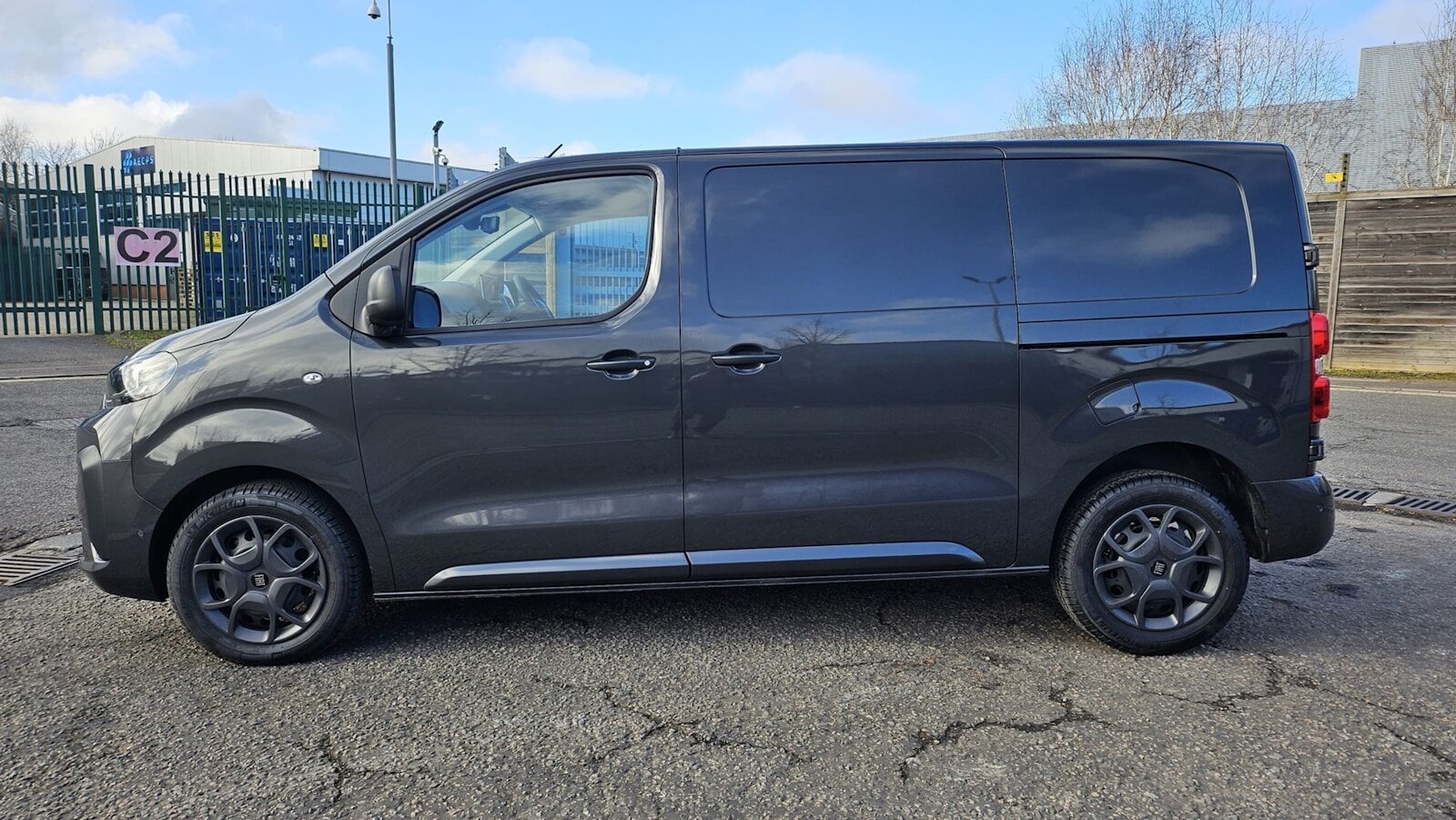 Dark grey panel van parked on a paved surface.